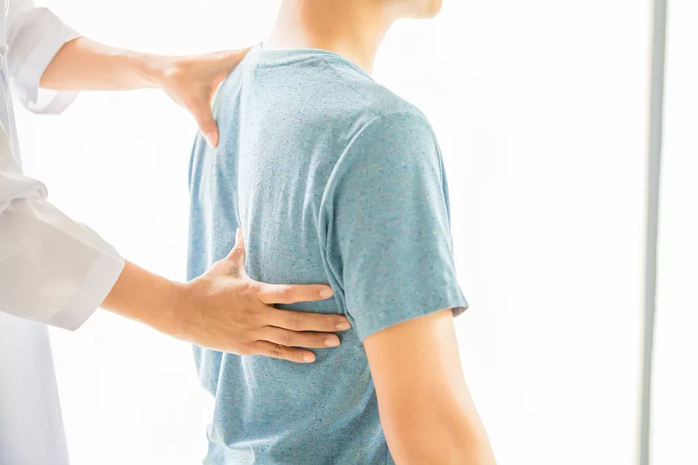 A healthcare professional conducts a spinal examination on a patient, indicative of a routine check-up for spinal fusion rehabilitation.